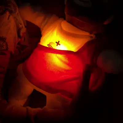 Peluche de Jesús encendido junto a un niño dormido